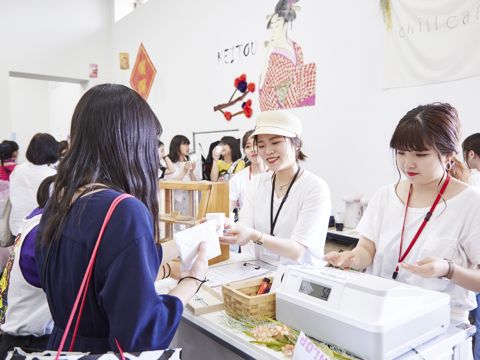 【写真コメント1】 夏の学生主催イベント、プレタポルテ展。学生オリジナルのショップを運営し、楽しくお出迎え。
