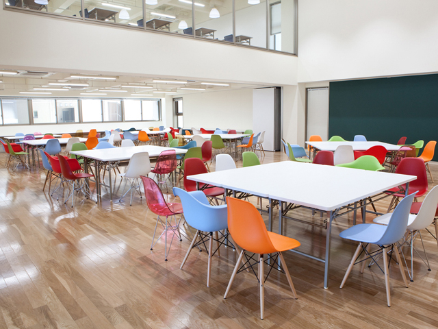 【2F_スクエアホール】常に開放された在学生のためのフリースペース。組み合わせ自由な机とカラフルなチェアで対話が生まれる場所。