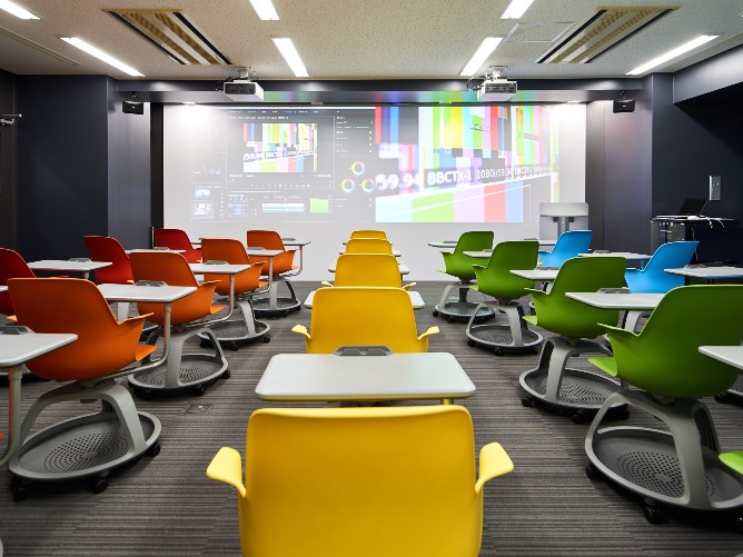 Ｗｅｂ動画クリエイター科の教室では、スクリーン幅６ｍの高解像度・高輝度プロジェクター(無線ＬＡＮ対応)を装備し、さまざまな作品を投影しながら授業をおこないます。